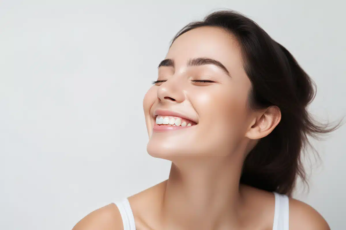 Head and shoulders of woman model touching glowing hydrated facial skin