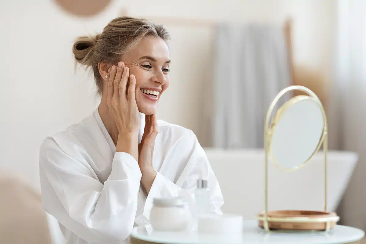 Smiling blonde woman making anti-aging face massage