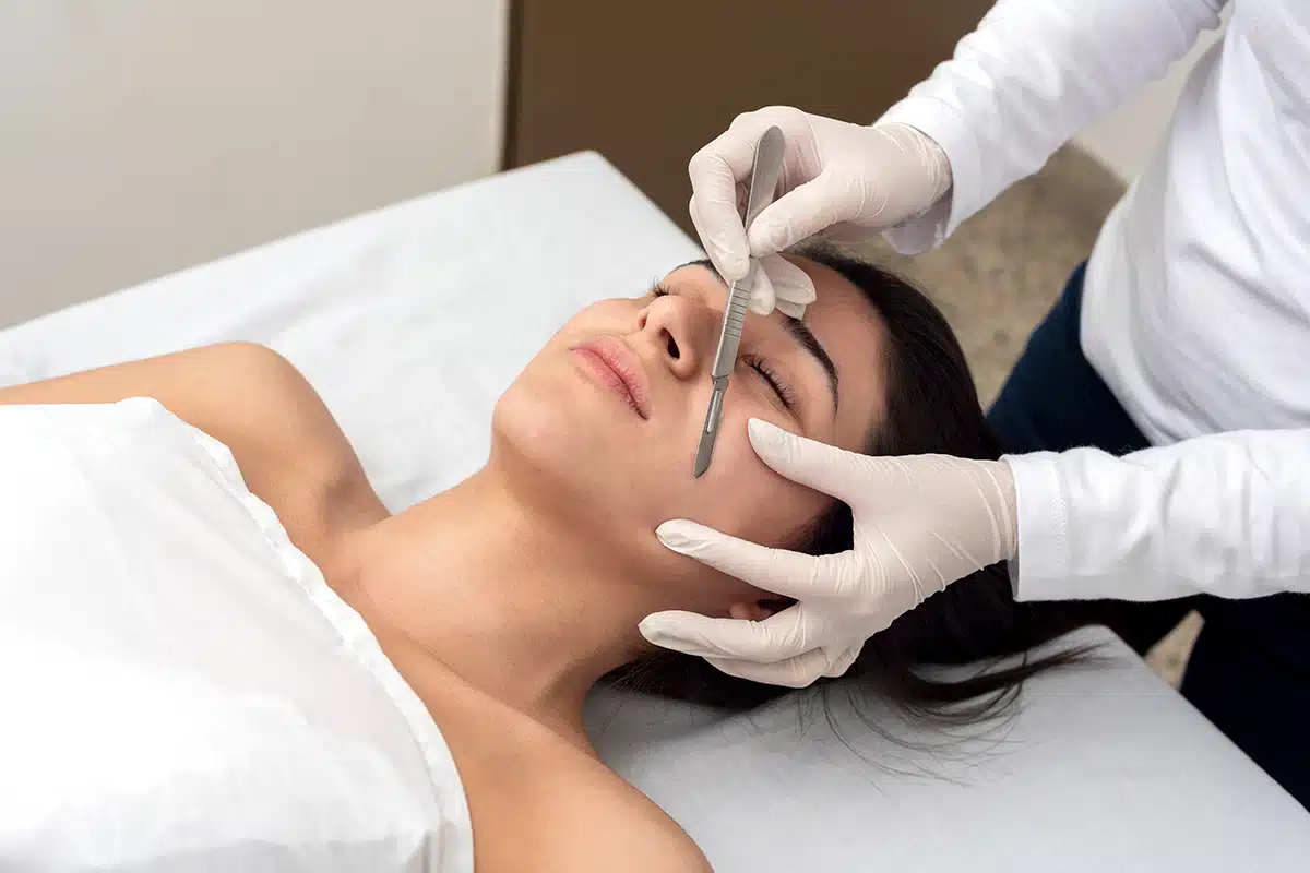 Young woman on a table in a beauty center performing a beauty treatment for facial skin with the dermaplaning technique